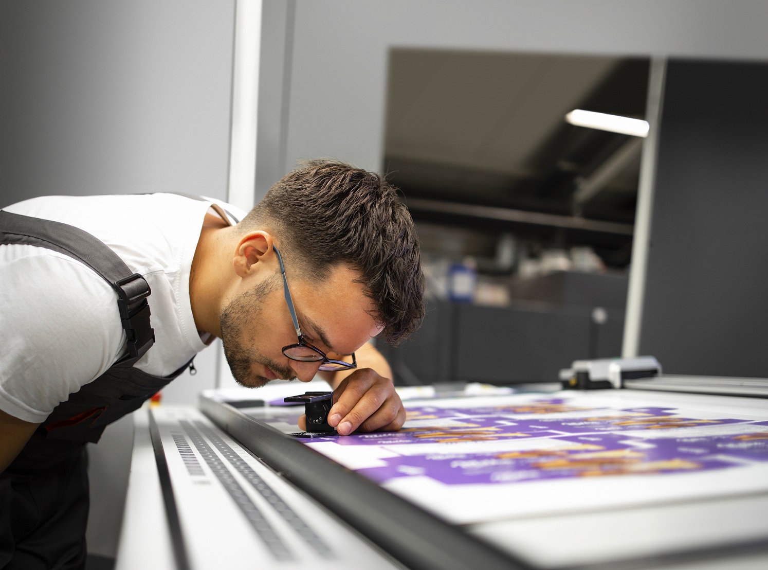 Worker checking print quality of graphics in modern printing hou